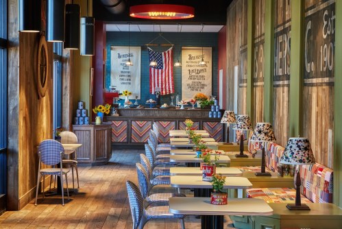 A cozy restaurant interior with colorful tables, lamps, and an American flag, featuring a welcoming atmosphere.