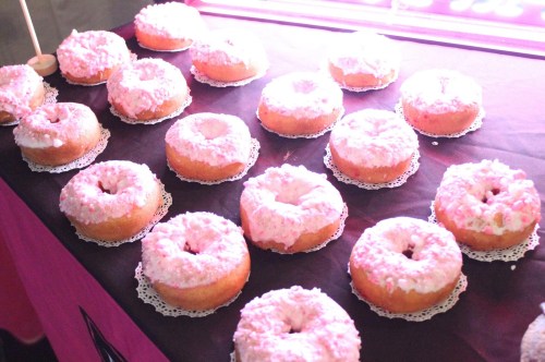 A display of pink-frosted donuts arranged on a table with lace doilies.