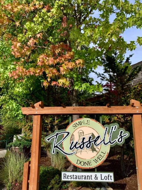 Sign for Russell's Restaurant & Loft surrounded by vibrant green and red foliage.