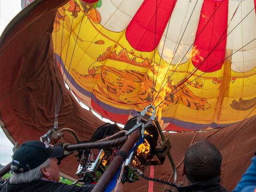 A hot air balloon being inflated, with flames from the burner illuminating the colorful canopy above.