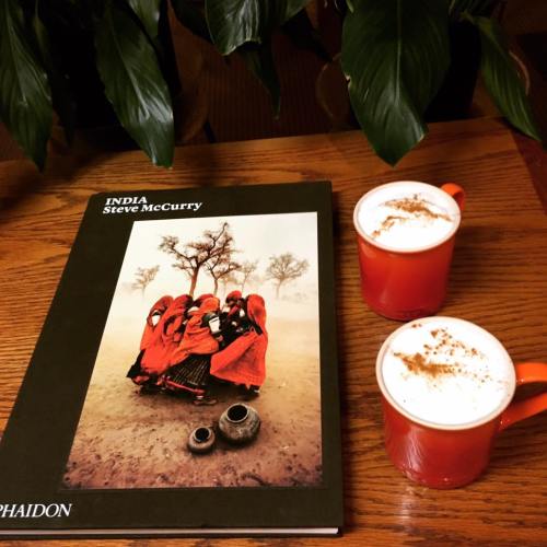 A book titled "India" by Steve McCurry, with two cups of coffee and greenery in the background.