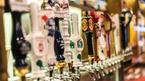 A row of colorful beer taps featuring various brands and designs in a bar setting.