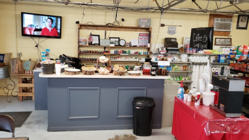 A cozy café counter with snacks, drinks, and a TV in the background, featuring a rustic decor and a welcoming atmosphere.