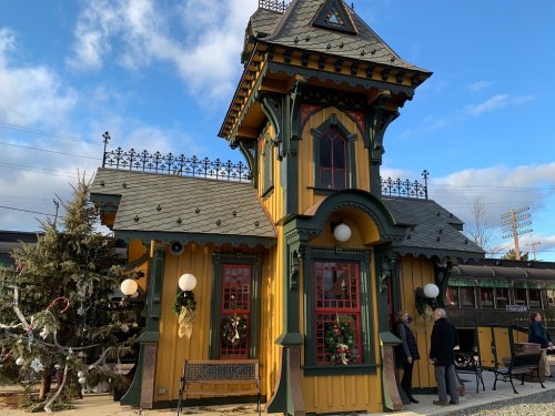 Colorful Victorian-style train station with festive decorations and people admiring the architecture.