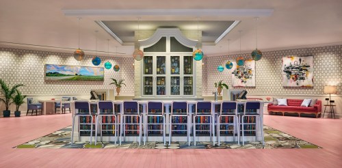 A modern, stylish interior featuring a bar with seating, colorful decor, and artwork on the walls.