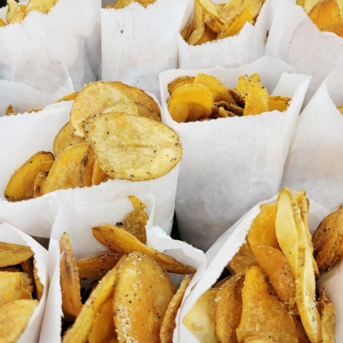 A close-up of paper bags filled with golden, crispy potato chips.