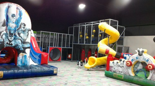 Indoor play area featuring inflatable slides, a climbing structure, and colorful play equipment.