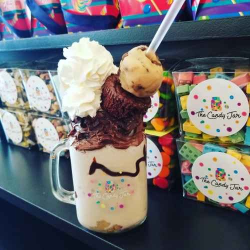 A decadent milkshake topped with whipped cream, chocolate, a brownie, and a scoop of cookie dough ice cream.