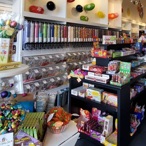 A colorful candy store interior filled with jars of sweets, candy displays, and various treats on shelves.