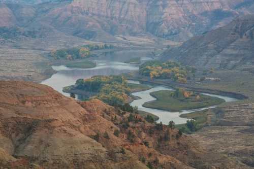 A winding river flows through a rugged landscape with colorful trees and hills in the background.