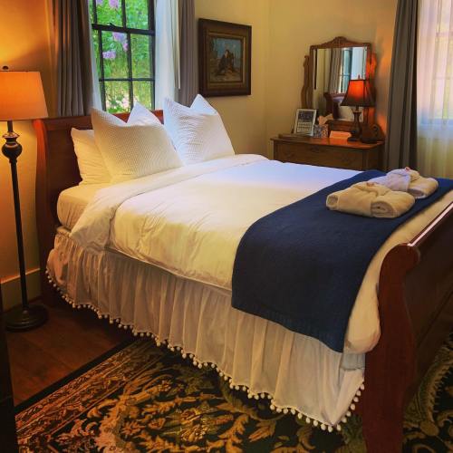Cozy bedroom with a neatly made bed, decorative pillows, a lamp, and a mirror reflecting natural light.
