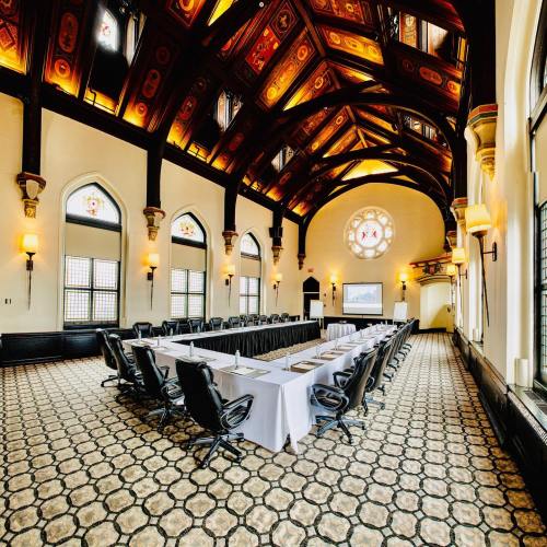 A spacious, elegantly designed meeting room with a long table, ornate ceiling, and large windows.