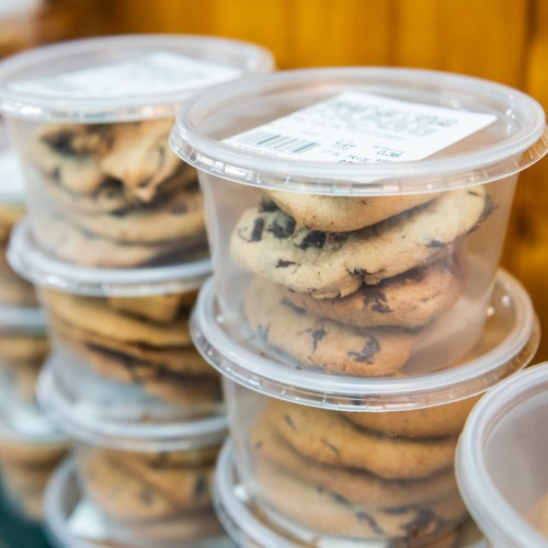 Clear containers stacked with chocolate chip cookies, showcasing their soft texture and golden-brown edges.