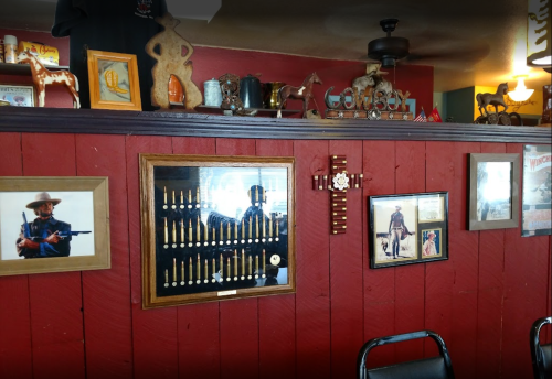 A rustic wall display featuring framed photos, decorative items, and a collection of pens in a cozy setting.