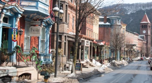 Charming street lined with colorful historic buildings, shops, and a clock tower, with snow on the ground.