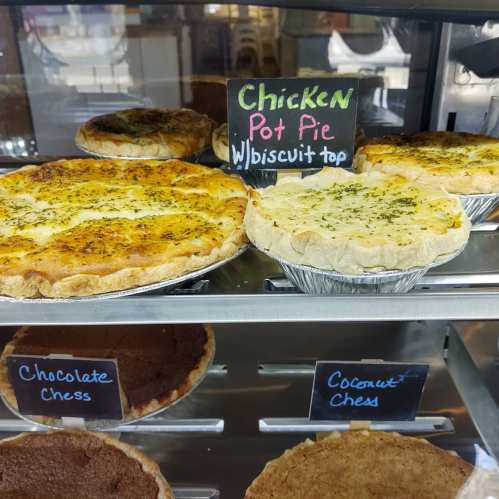 Display case with chicken pot pie topped with biscuits, and chocolate and coconut chess pies.