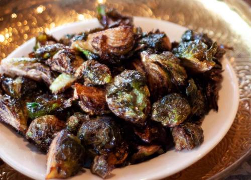 A plate of crispy, roasted Brussels sprouts with a golden-brown exterior, garnished and ready to serve.