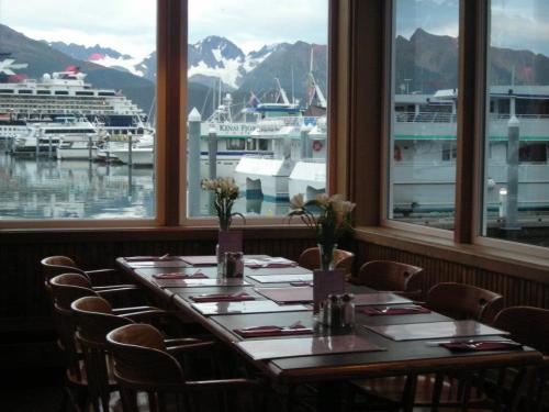 A dining area with a large table, overlooking a harbor filled with boats and mountains in the background.