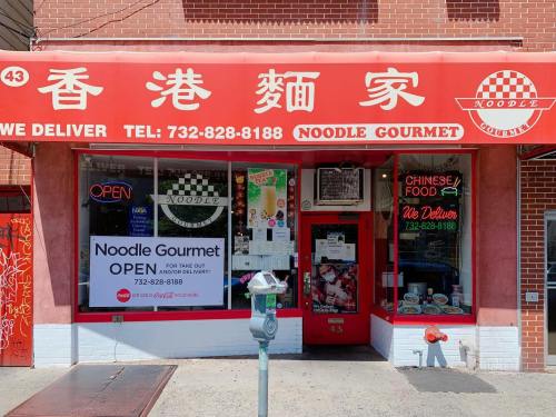 A red storefront with "Noodle Gourmet" signage, open for business, featuring a delivery phone number and Chinese food options.