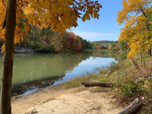 A serene river scene surrounded by autumn foliage, with colorful trees reflecting in the calm water.