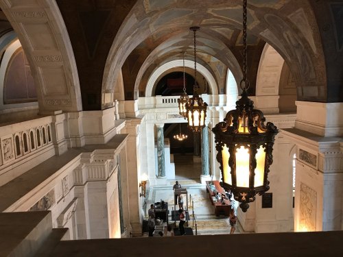 Interior view of a grand hall with arched ceilings and ornate chandeliers, showcasing elegant architecture and furnishings.
