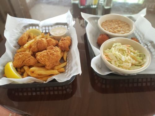 Two baskets of food: one with fried fish and fries, the other with coleslaw and baked beans.