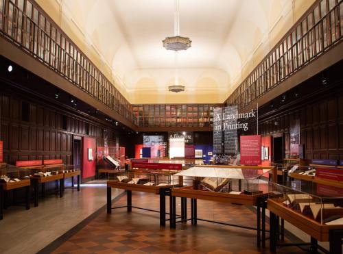 Interior of a museum gallery featuring wooden displays, artwork, and informational panels in a well-lit space.