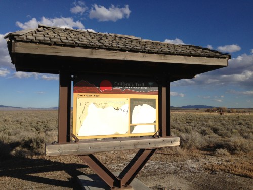 Signpost for the California Trail, featuring maps and information, set against a wide, open landscape.