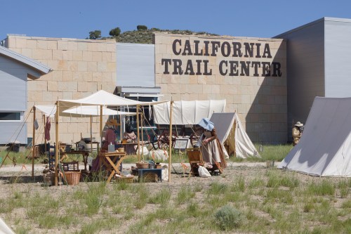 A historical reenactment scene at the California Trail Center, featuring tents and period-appropriate activities.