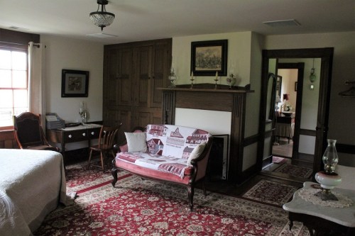 Cozy room featuring a bed, vintage furniture, a desk, and a decorative rug, with warm lighting and classic decor.