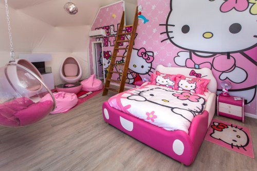 A pink-themed bedroom featuring Hello Kitty decor, a round chair, bean bags, and a playful design.