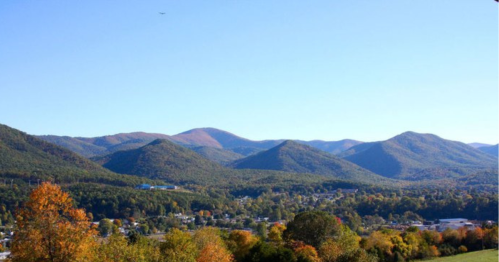 A scenic view of mountains with autumn foliage under a clear blue sky.