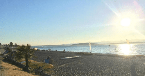 A serene beach scene at sunset, with surfboards on the sand and gentle waves lapping at the shore.