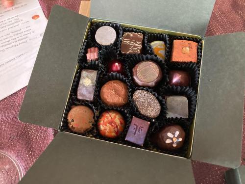 A box of assorted chocolates in various shapes and colors, arranged neatly in black liners.