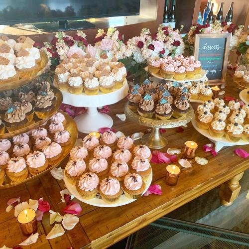 A beautifully arranged dessert table featuring various cupcakes, flowers, and candles, creating an elegant display.
