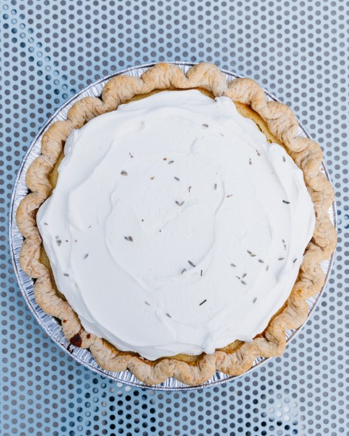 A round pie with a golden crust topped with a smooth layer of whipped cream and sprinkled with herbs.