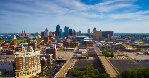 Aerial view of a city skyline with modern buildings, blue sky, and empty streets in the foreground.