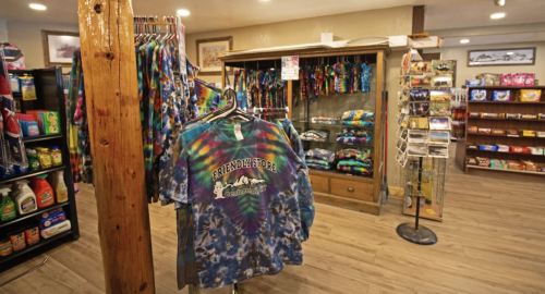 A colorful tie-dye shirt hangs in a store filled with various merchandise and snacks.