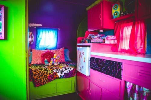 A colorful, vibrant bedroom with a leopard print bedspread, plush toys, and bright green and pink walls.
