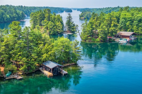 A scenic view of lush green islands surrounded by calm blue water, with boats and docks visible along the shoreline.