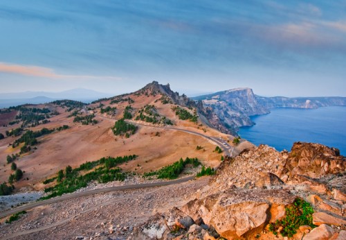 A scenic view of a rugged coastline with rocky hills and a calm blue sea under a clear sky.
