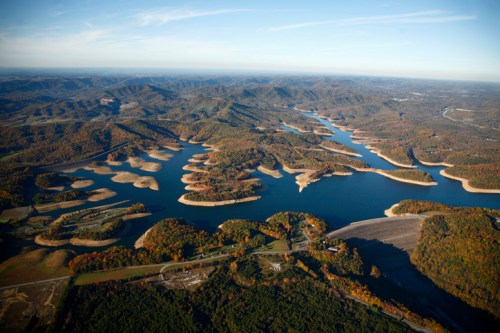 Aerial view of a winding river surrounded by colorful autumn foliage and rolling hills.