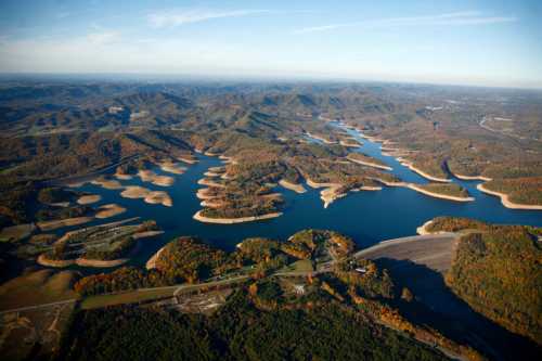 Aerial view of a winding river surrounded by colorful autumn foliage and rolling hills.