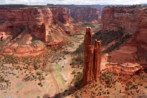 A stunning view of red rock formations and a winding river in a canyon landscape under a blue sky.