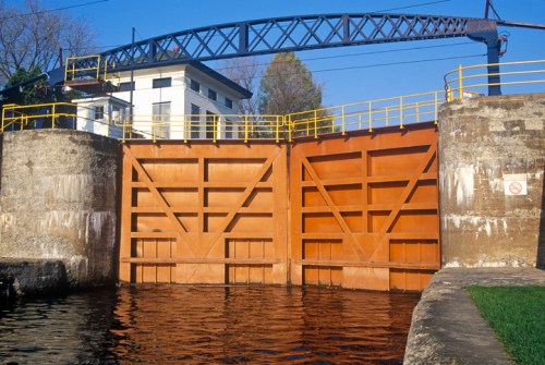 A large, closed lock gate with a blue crane above, surrounded by concrete walls and water below.