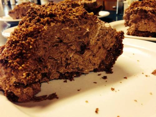 A close-up of a chocolate dessert with a crumbly topping, partially eaten, on a white plate.