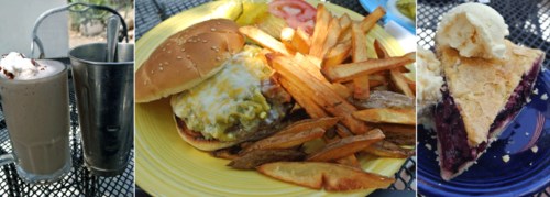 A plate with a cheeseburger, fries, and a slice of pie with ice cream, alongside two milkshakes on a table.