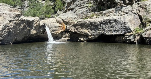 A small waterfall tumbles over a rock ledge and into a large natural pool in South Dakota.