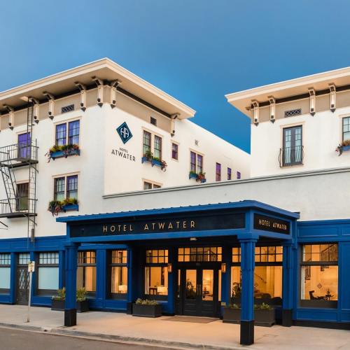 Exterior view of Hotel Atwater, featuring a blue entrance and decorative flowers under a clear evening sky.