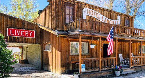 A rustic wooden building with a sign reading "Hotel Lamoule" and an American flag, featuring a livery entrance.